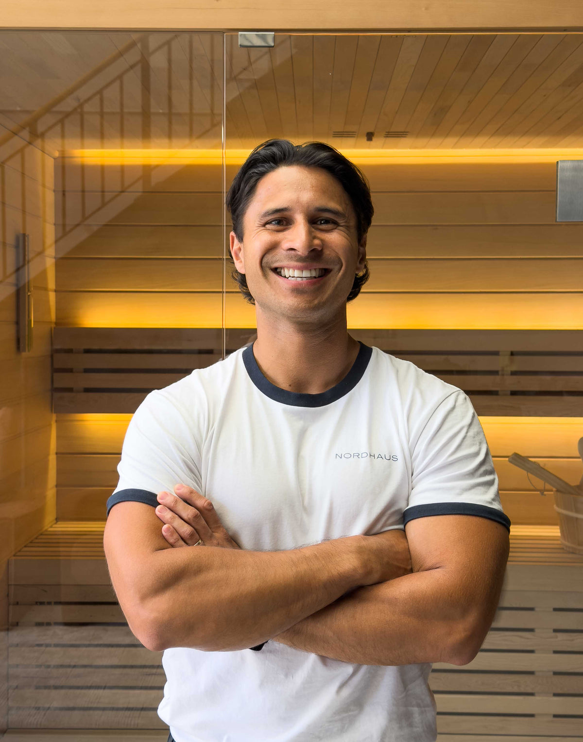 John from the Nordhaus customer support team smiling with arms crossed in front of a Nordhaus sauna