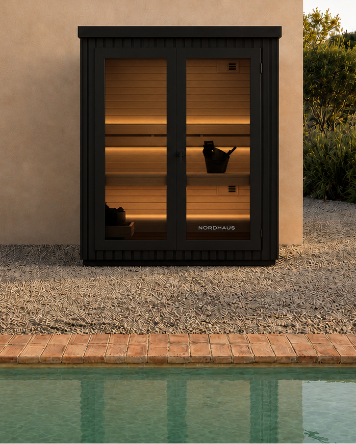 Black outdoor sauna with glass doors next to a pool and beige wall