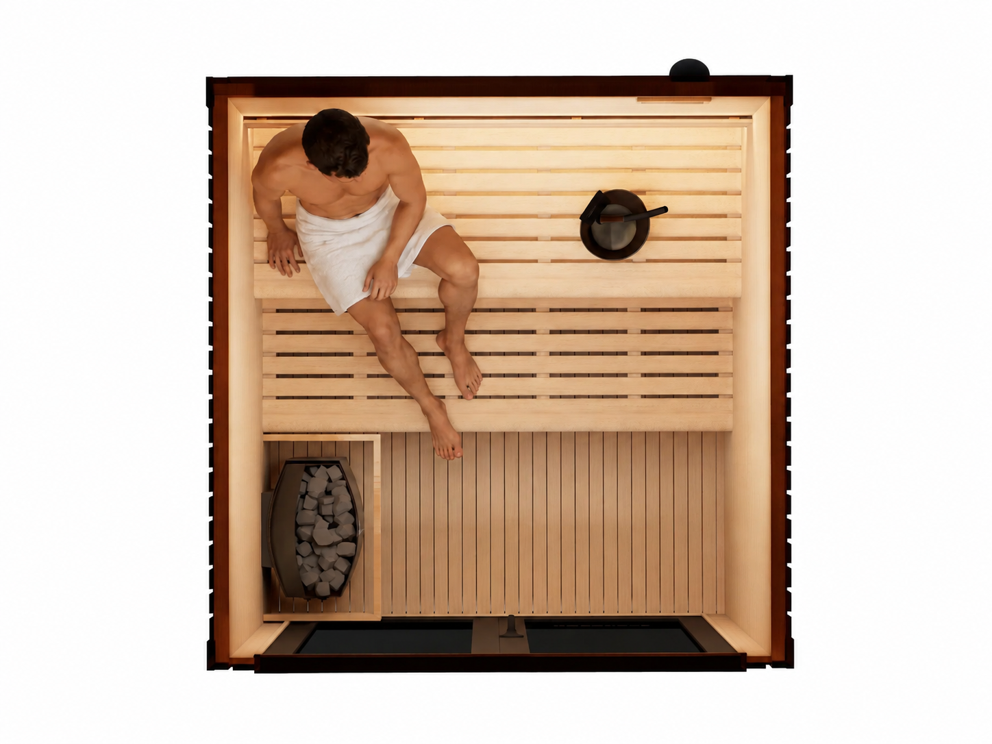 Top-down view of a wooden sauna interior with a person sitting on the upper bench wrapped in a white towel, a black metal pot on the shelf, and a fire basket with logs on the lower left.