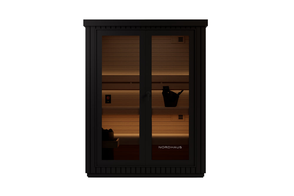 Black outdoor traditional sauna with matte aluminium cladding, warm timber interior, tiered benches, LED lighting and a full glass front door.