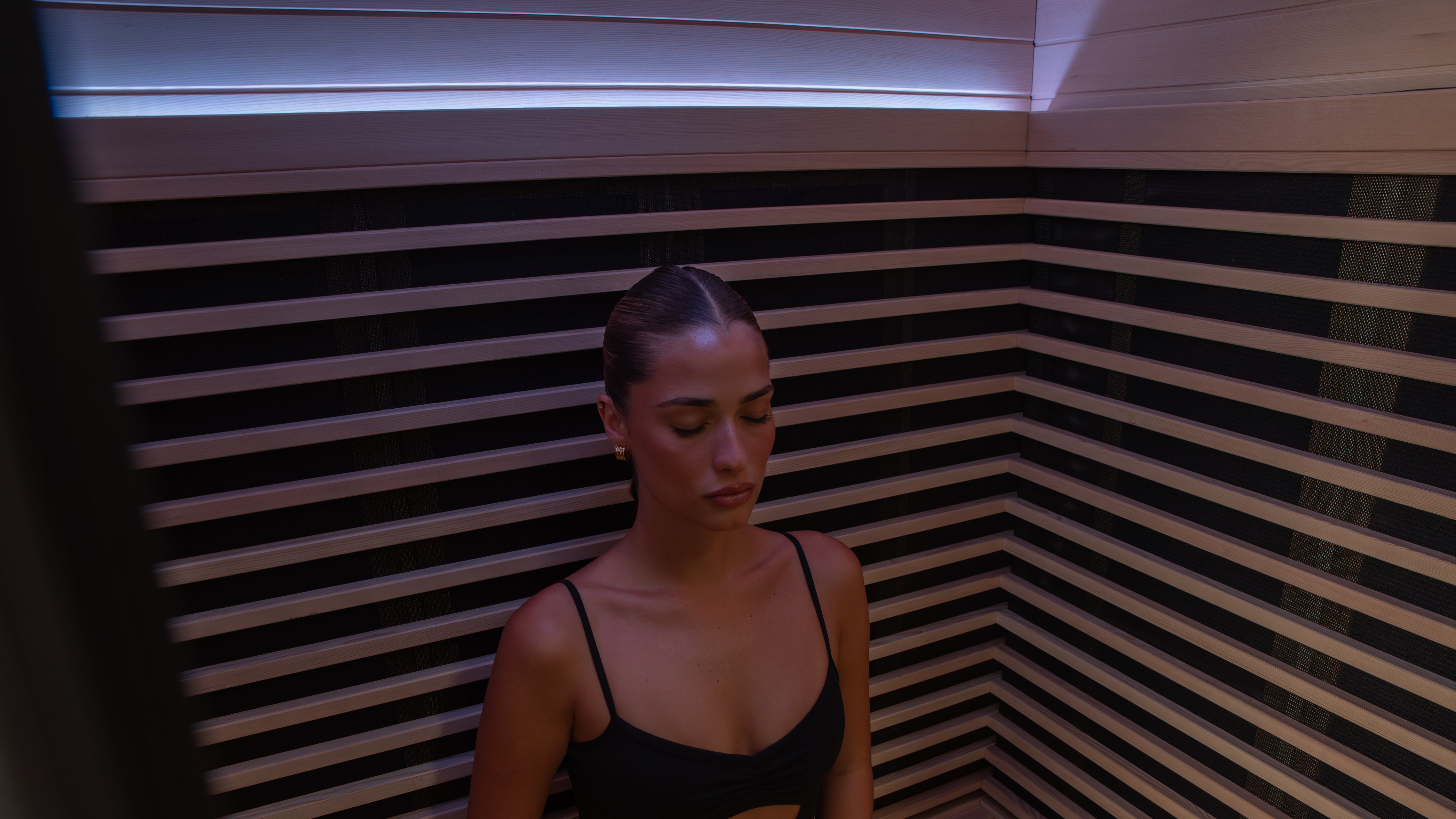 Nordhaus full spectrum infrared sauna with woman relaxing inside, premium home wellness and recovery setup